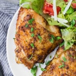 Air fryer chicken thighs on a plate with a salad.