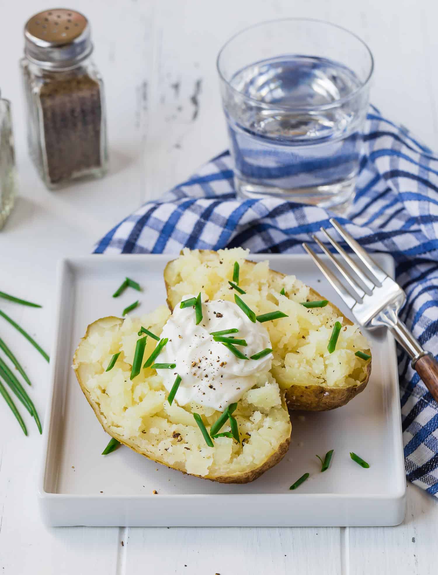 Baked potato on a square white plate.