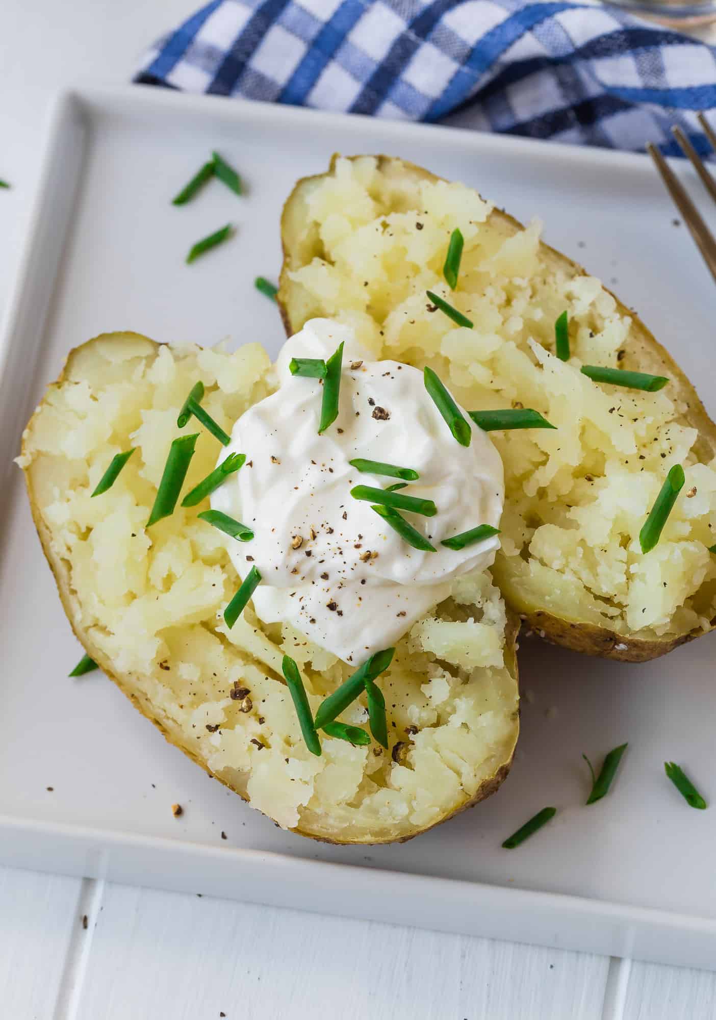 Baked potato cut open and topped with sour cream and chives.