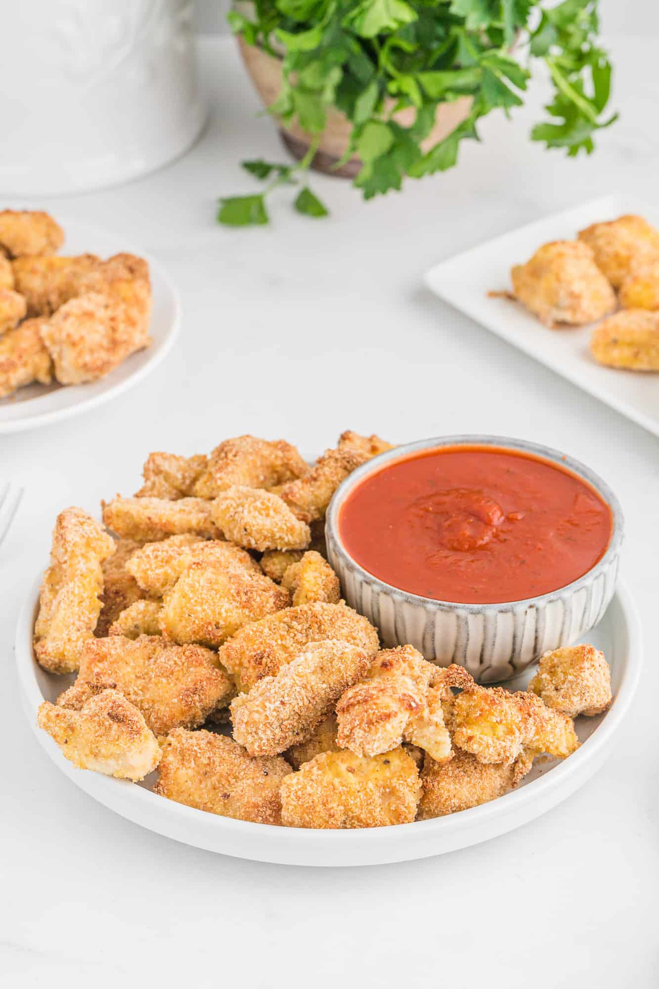 Breaded chicken nuggets on a serving platter with marinara.