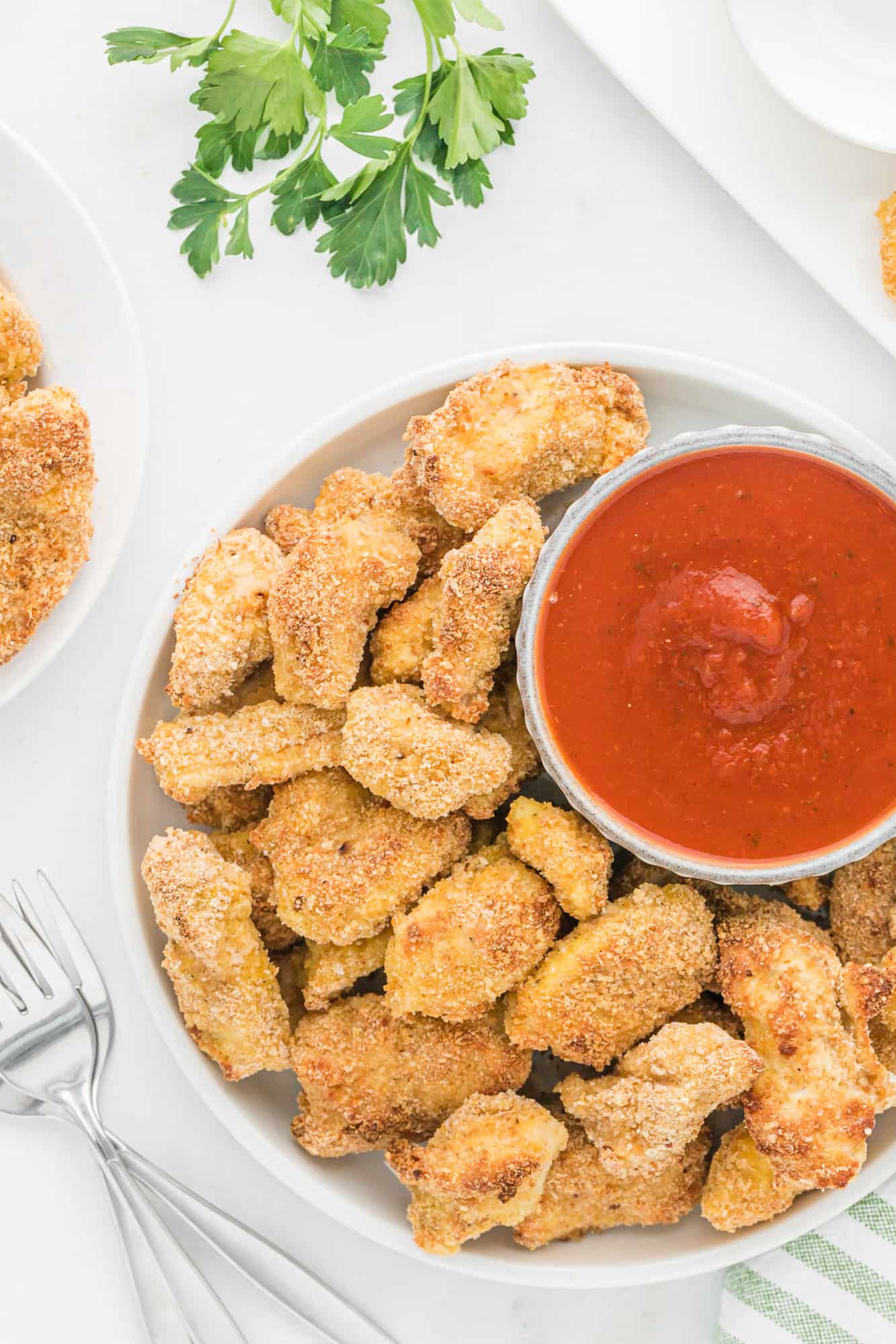 Chicken nuggets on a white plate with marinara sauce.