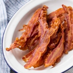 Crispy baked bacon on a white platter.