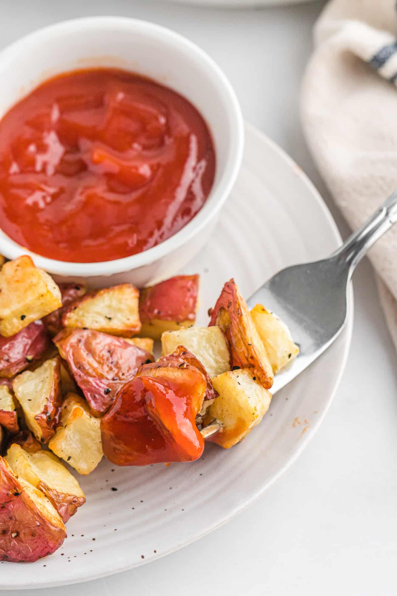 Roasted potatoes on a plate with ketchup.