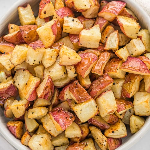 Crispy roasted potatoes in a round white bowl.