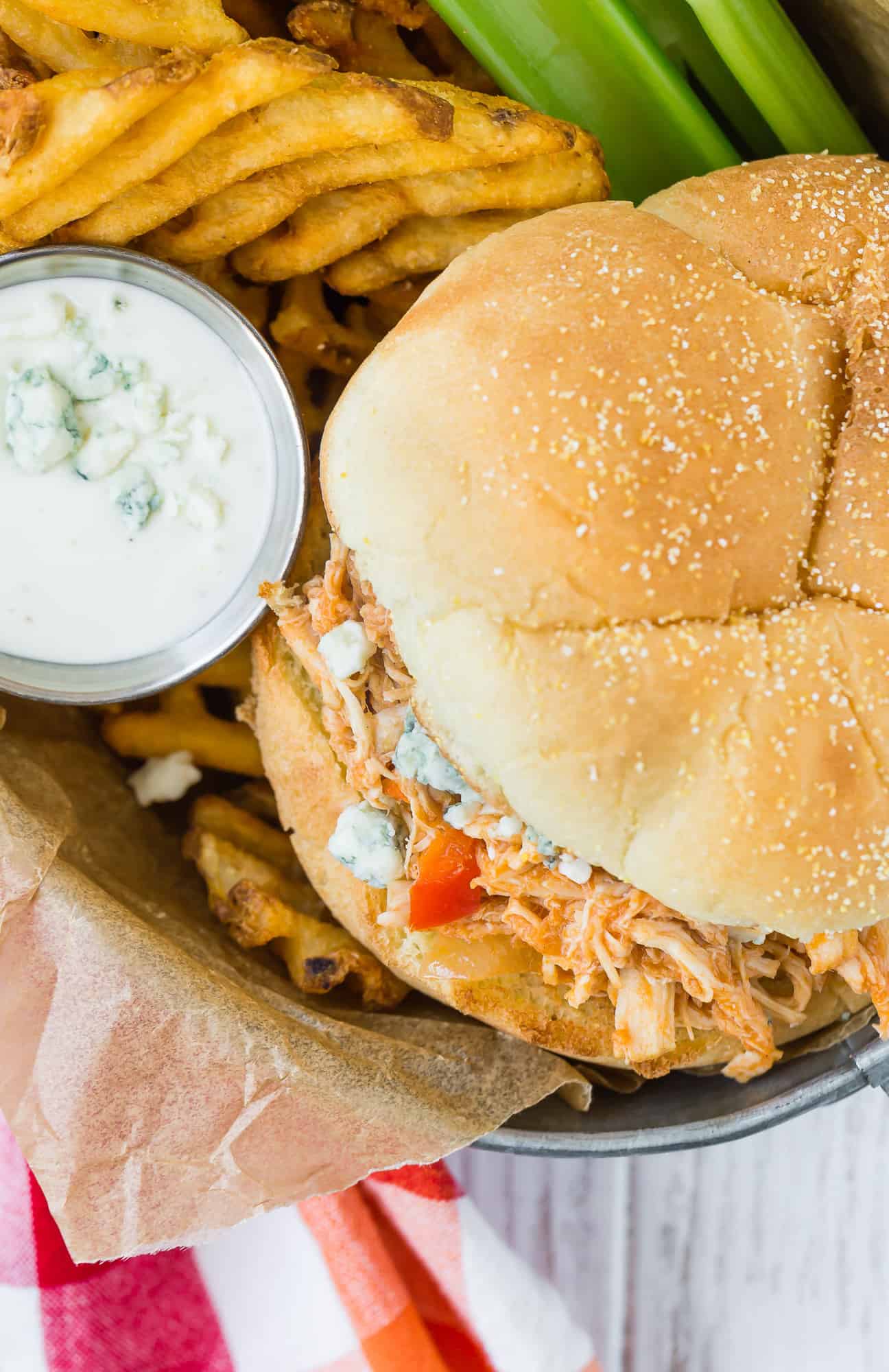 Overhead view of sandwich with fries and blue cheese dressing.