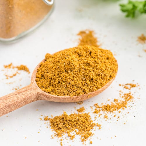 Homemade curry powder on a small wooden spoon.