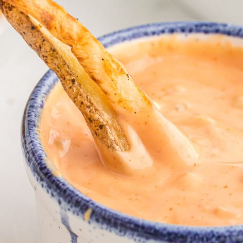 Fries being dipped into fry sauce.