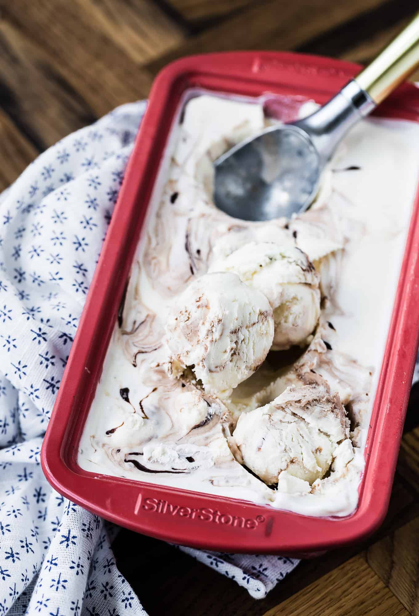 Ice cream in a red loaf pan being scooped.