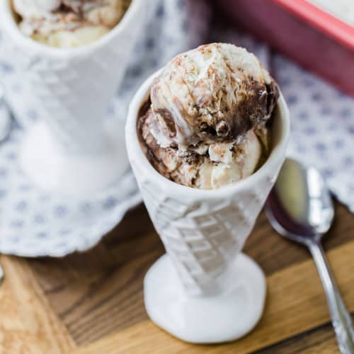 Fudge swirl ice cream in a white cone shaped bowl.