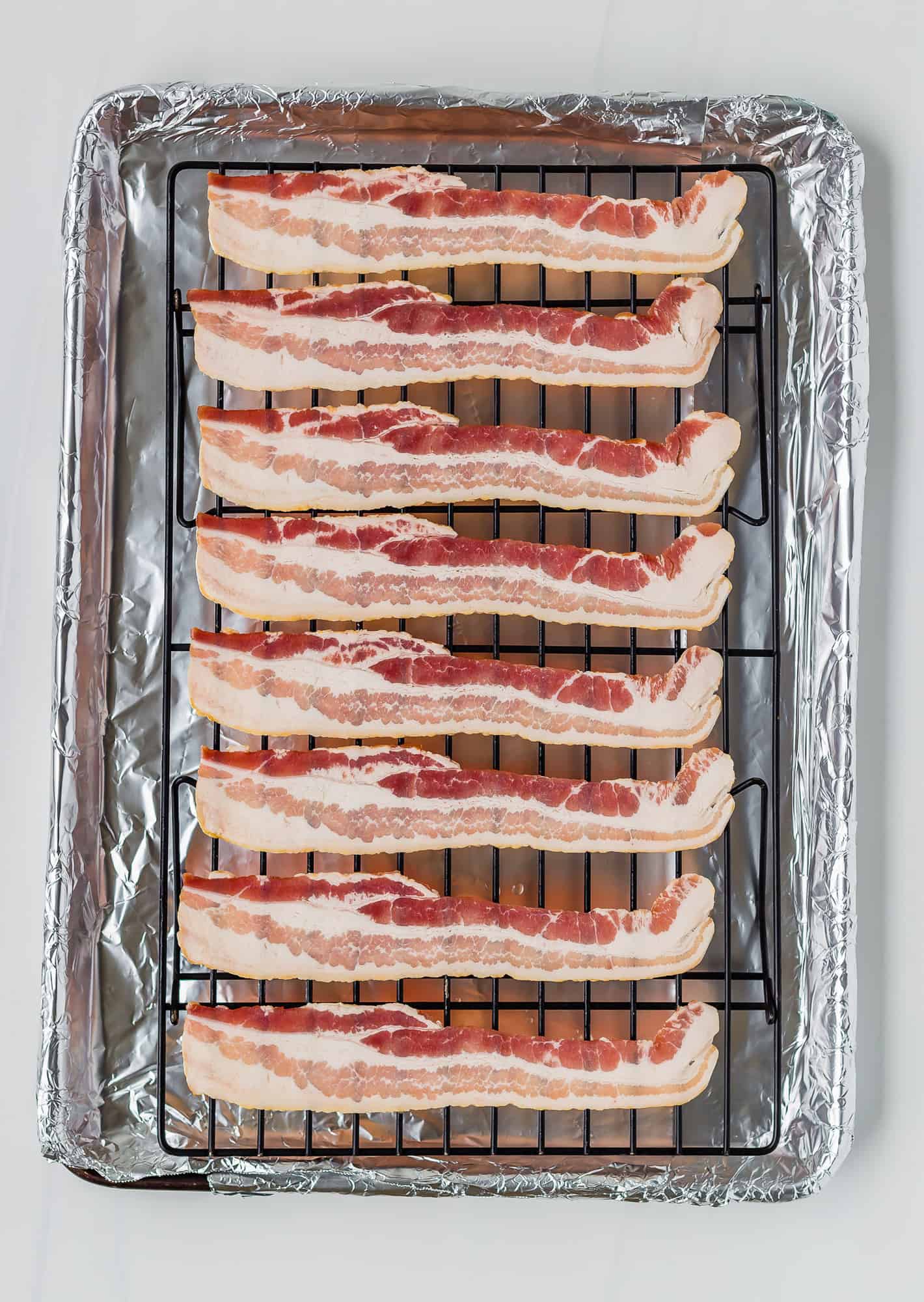 Uncooked bacon on a baking rack.