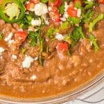 Instant Pot refried beans with cilantro, cheese, and tomatoes.