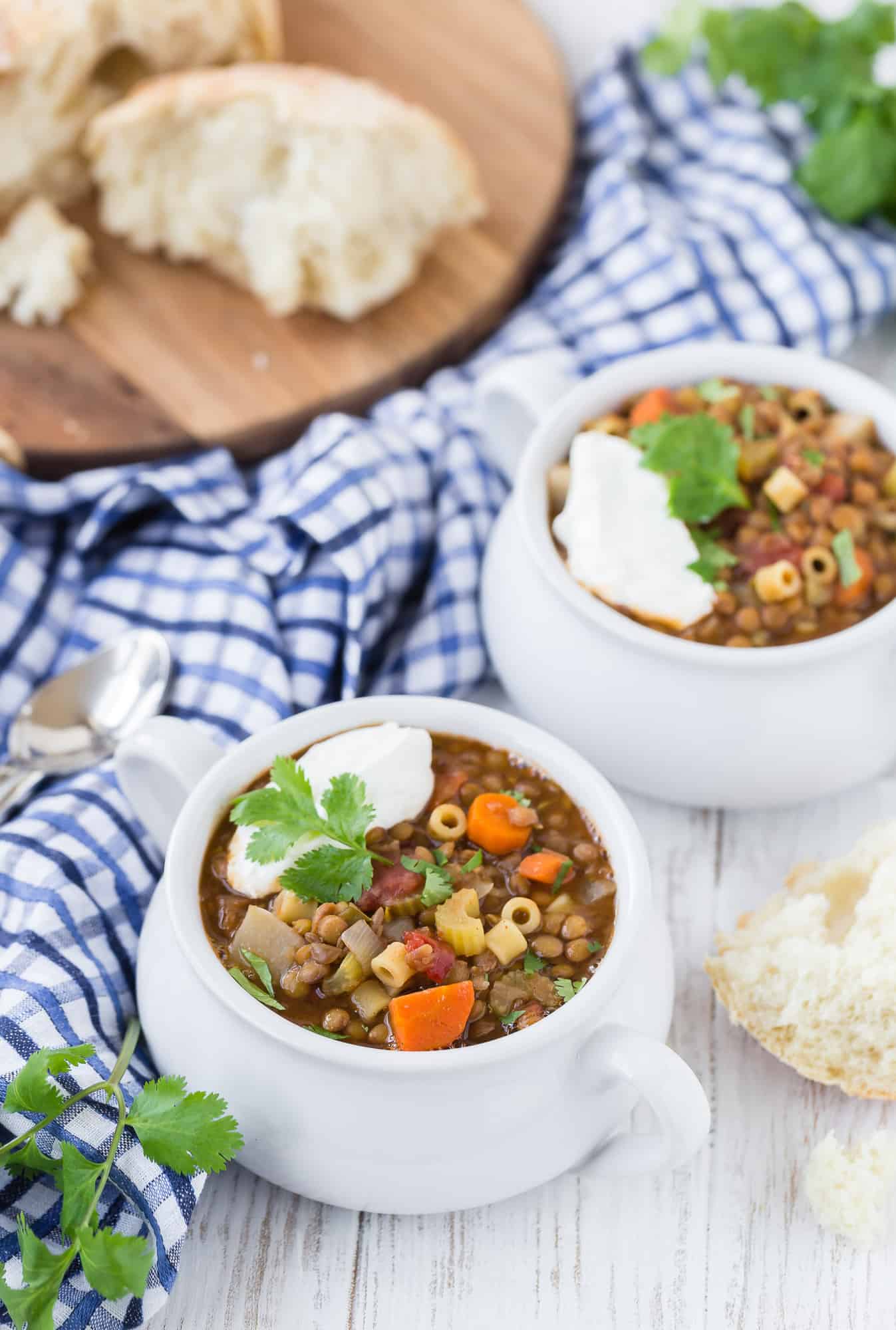 Image of two bowls of hearty lentil soup made with brown lentils, carrots, celery, tomatoes, and pasta. 