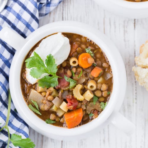 Lentil soup with pasta, topped with yogurt and cilantro.