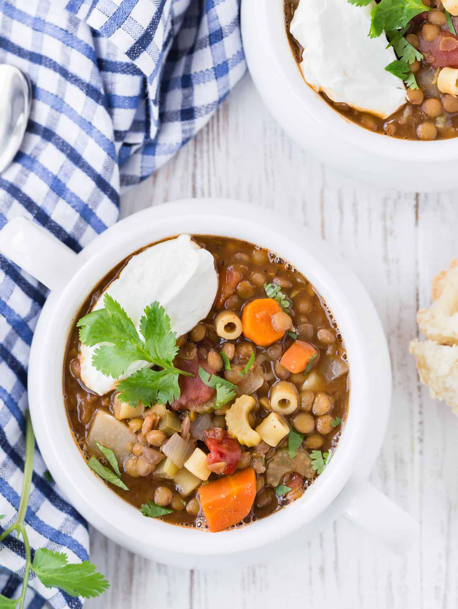 Overhead image of a bowl of lentil and pasta soup, garnished with greek yogurt and cilantro.