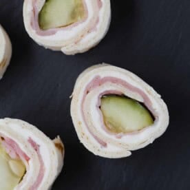 Pickle roll ups with ham on a black background.