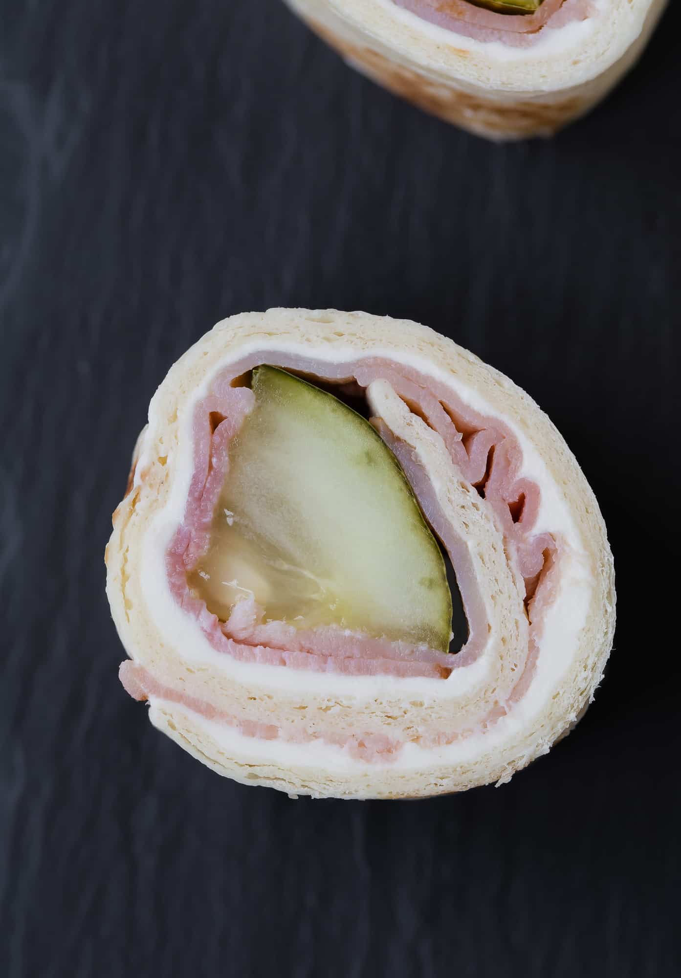 Pickle, ham, and cream cheese rolled in a tortilla.