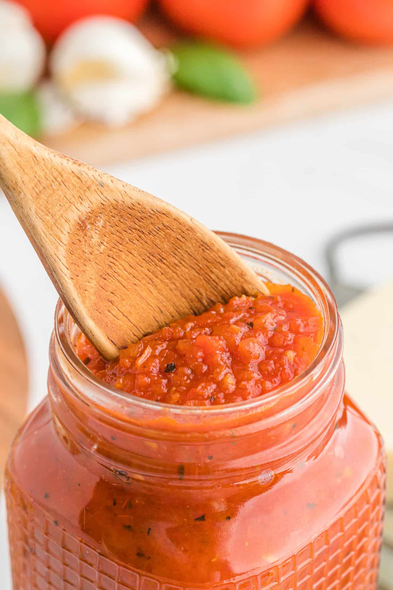 Close up of pizza sauce being scooped out of a jar.