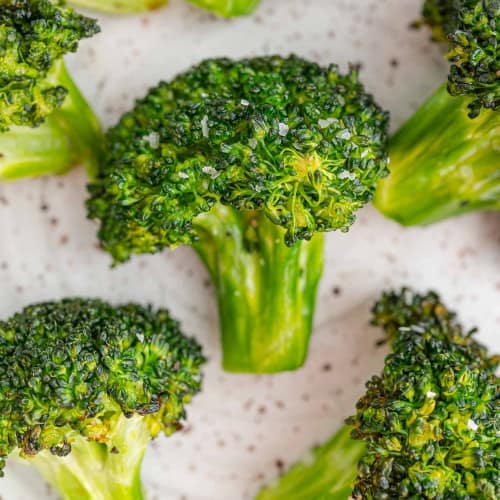 Florets of air fryer broccoli on white background.