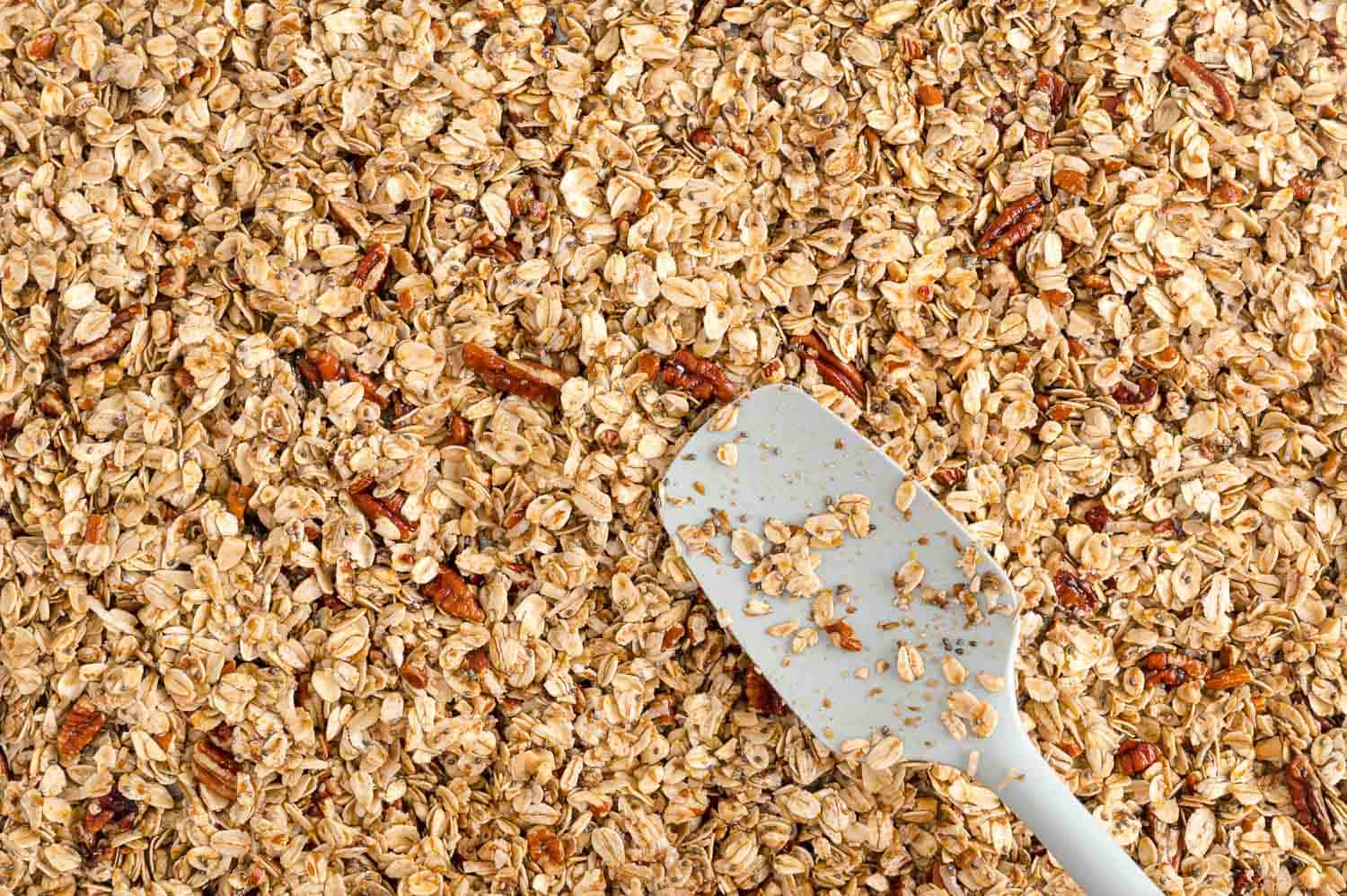 Unbaked granola being spread on pan.