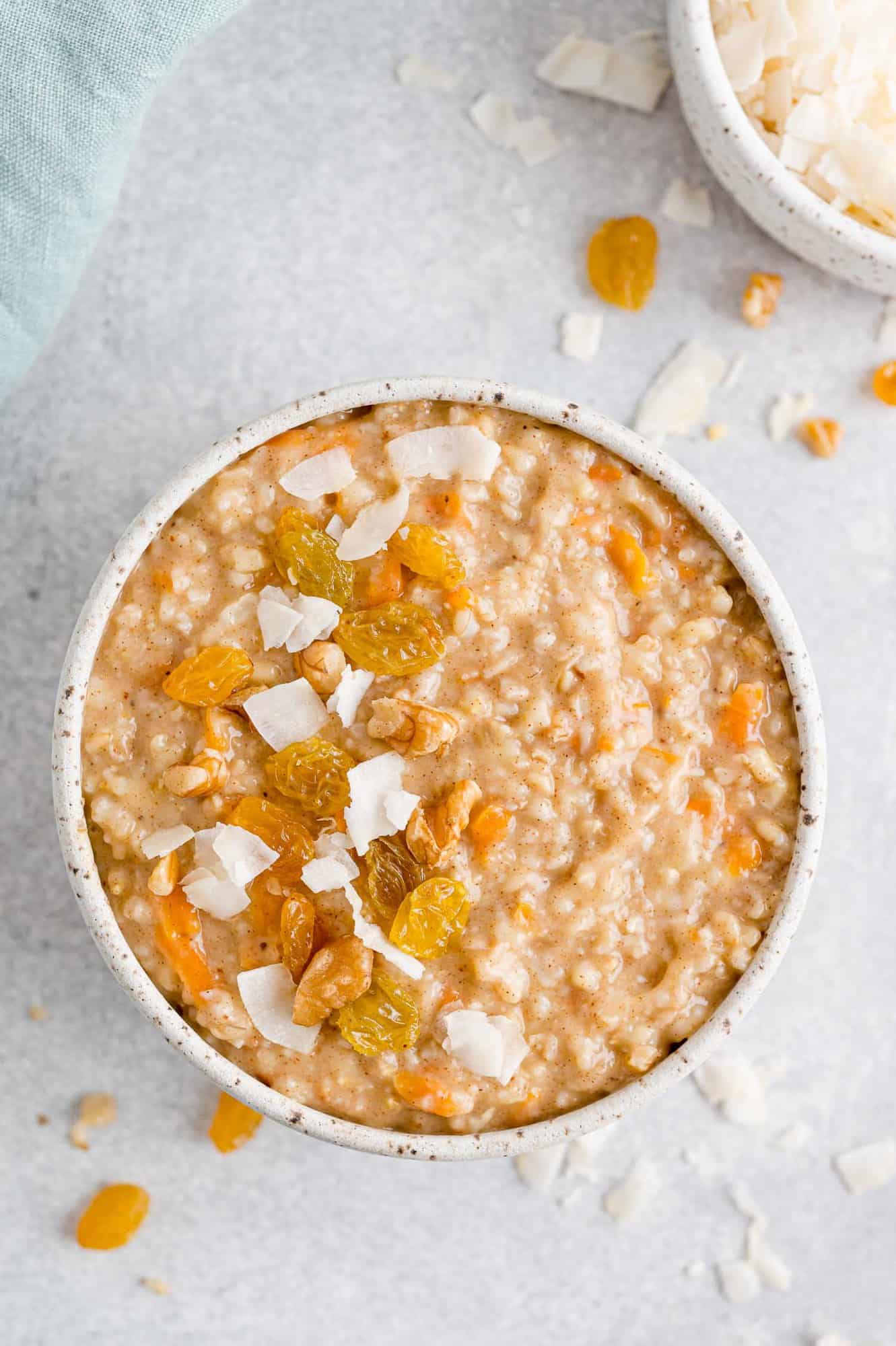 Carrot oatmeal with toppings including raisins, walnuts, coconut.