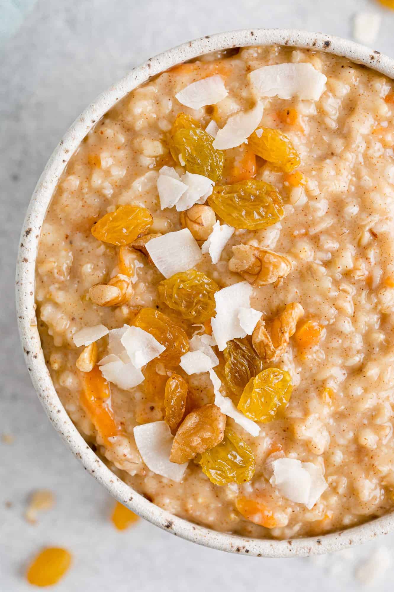 Carrot cake oatmeal topped with coconut, raisins, and shaved carrots.