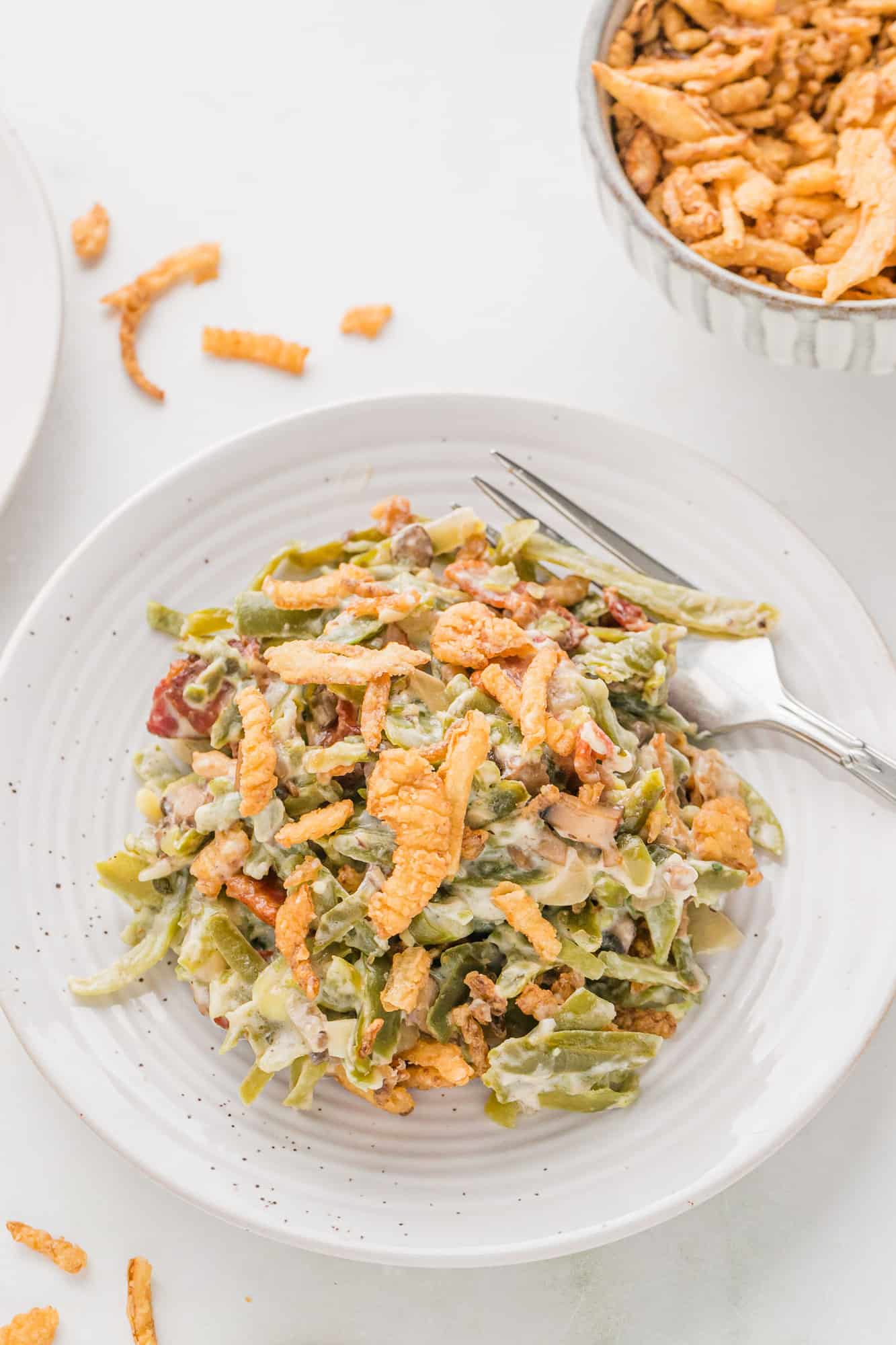 Plated casserole with green beans, mushrooms, bacon, and crisoy onions.