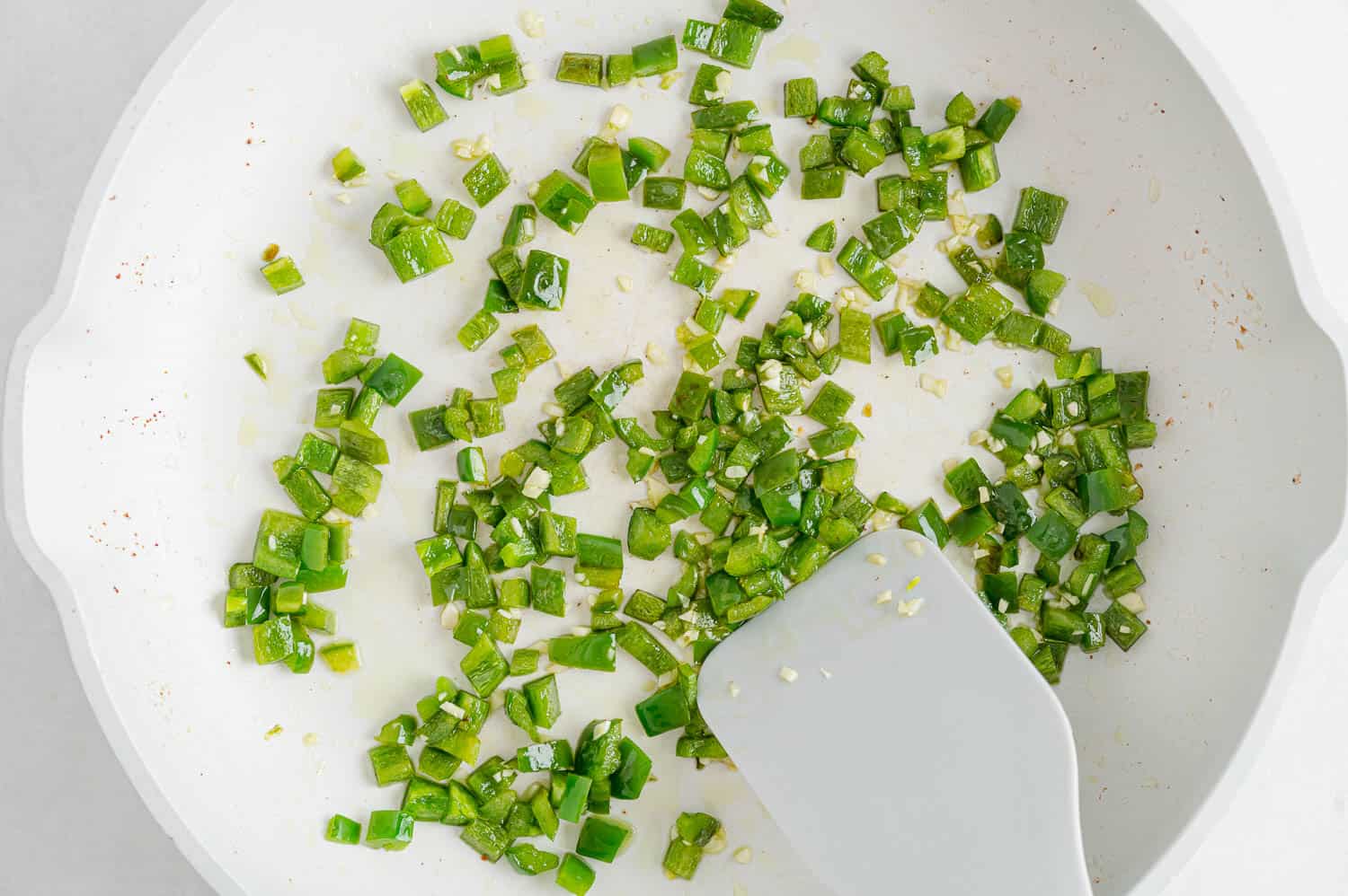 Diced jalapeño in a frying pan.