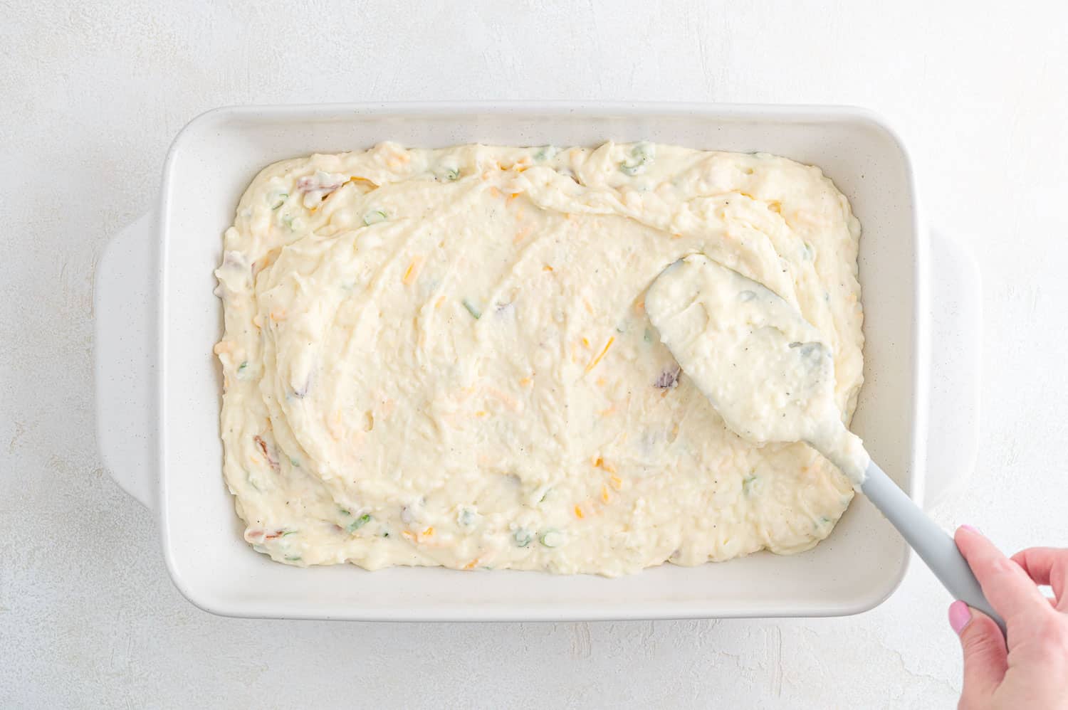 Mashed potatoes being spread in a pan.