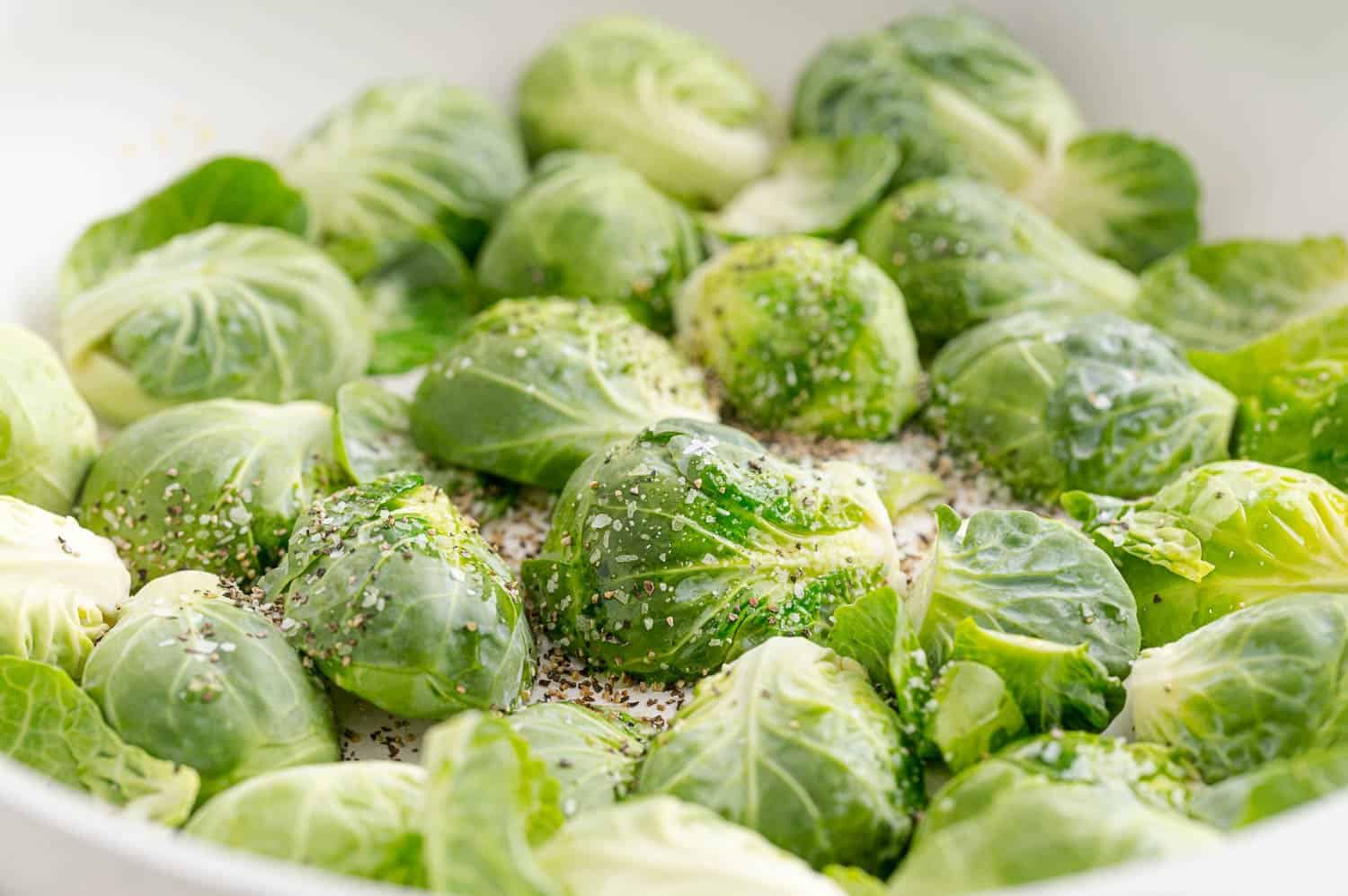 Brussels sprouts in pan, sprinkled with salt and pepper.
