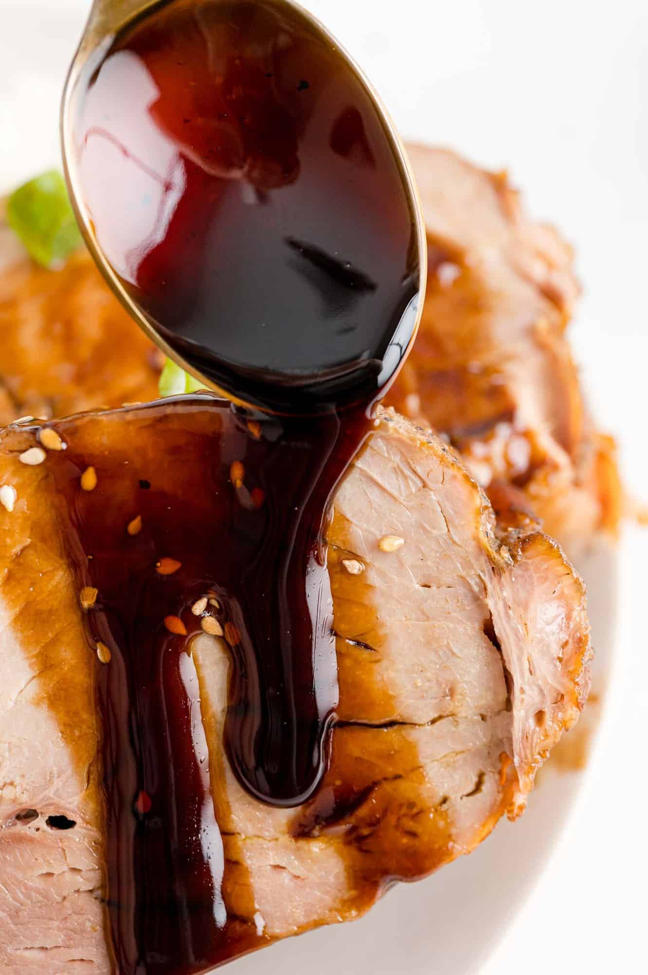 Balsamic glaze being poured on pork loin slices.