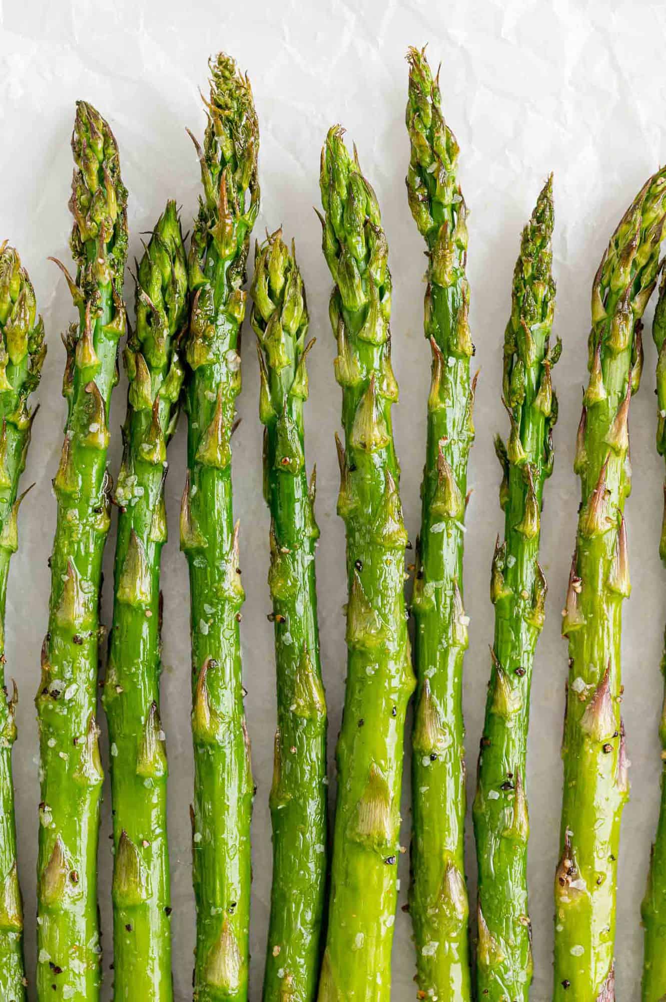 Air fryer asparagus lined up in a single layer on a white background.