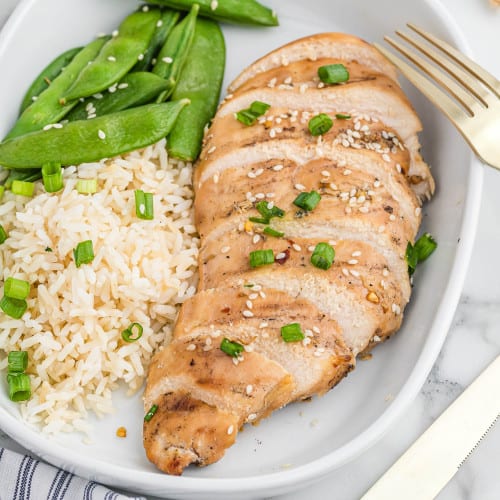 Sliced cooked chicken breast with sesame seeds and green onion.