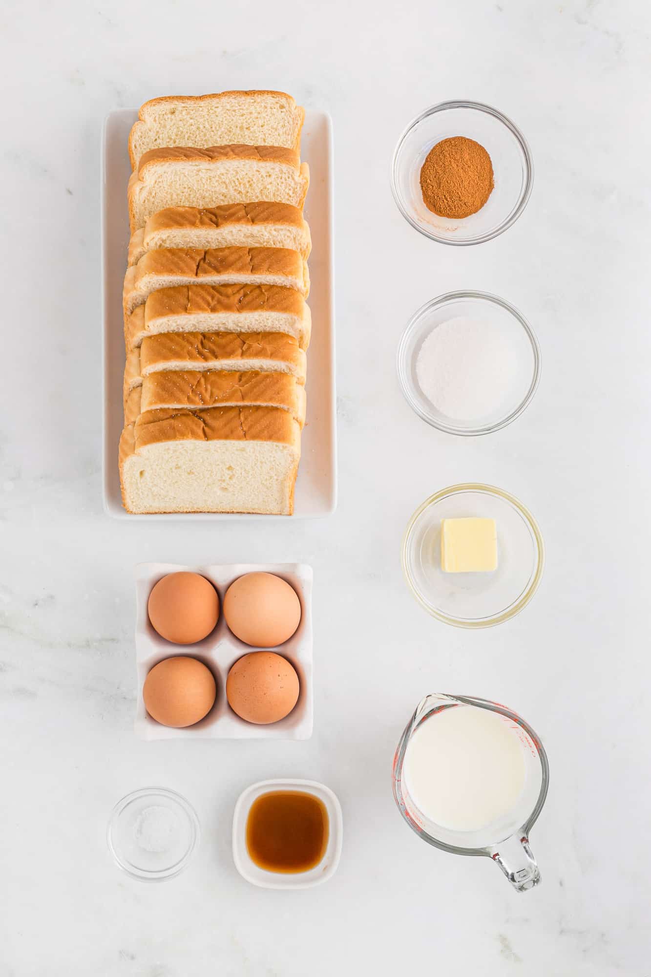 Overhead view of French toast ingredients including bread and eggs.