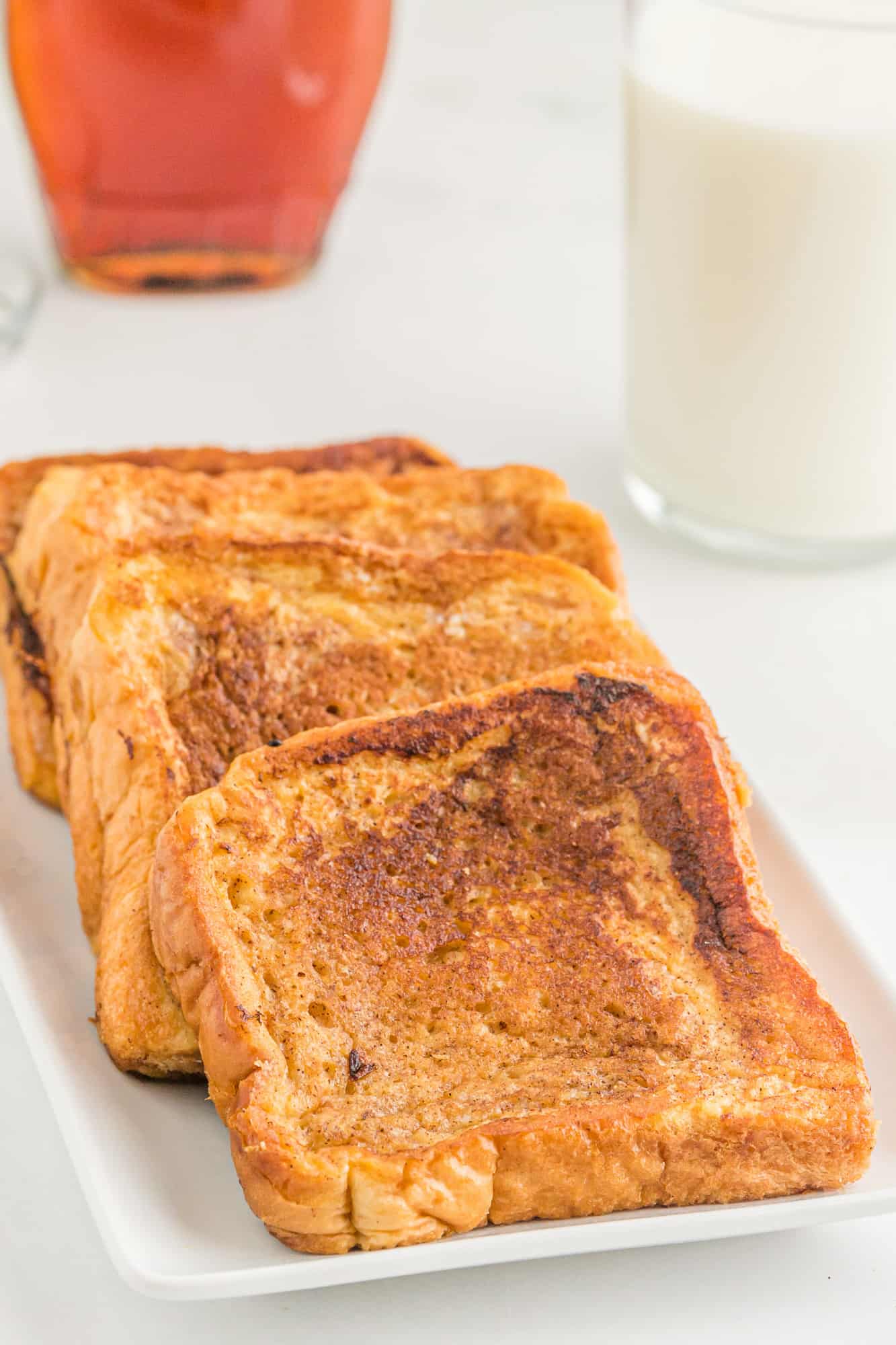 Cooked French toast slices lined up on a plate.