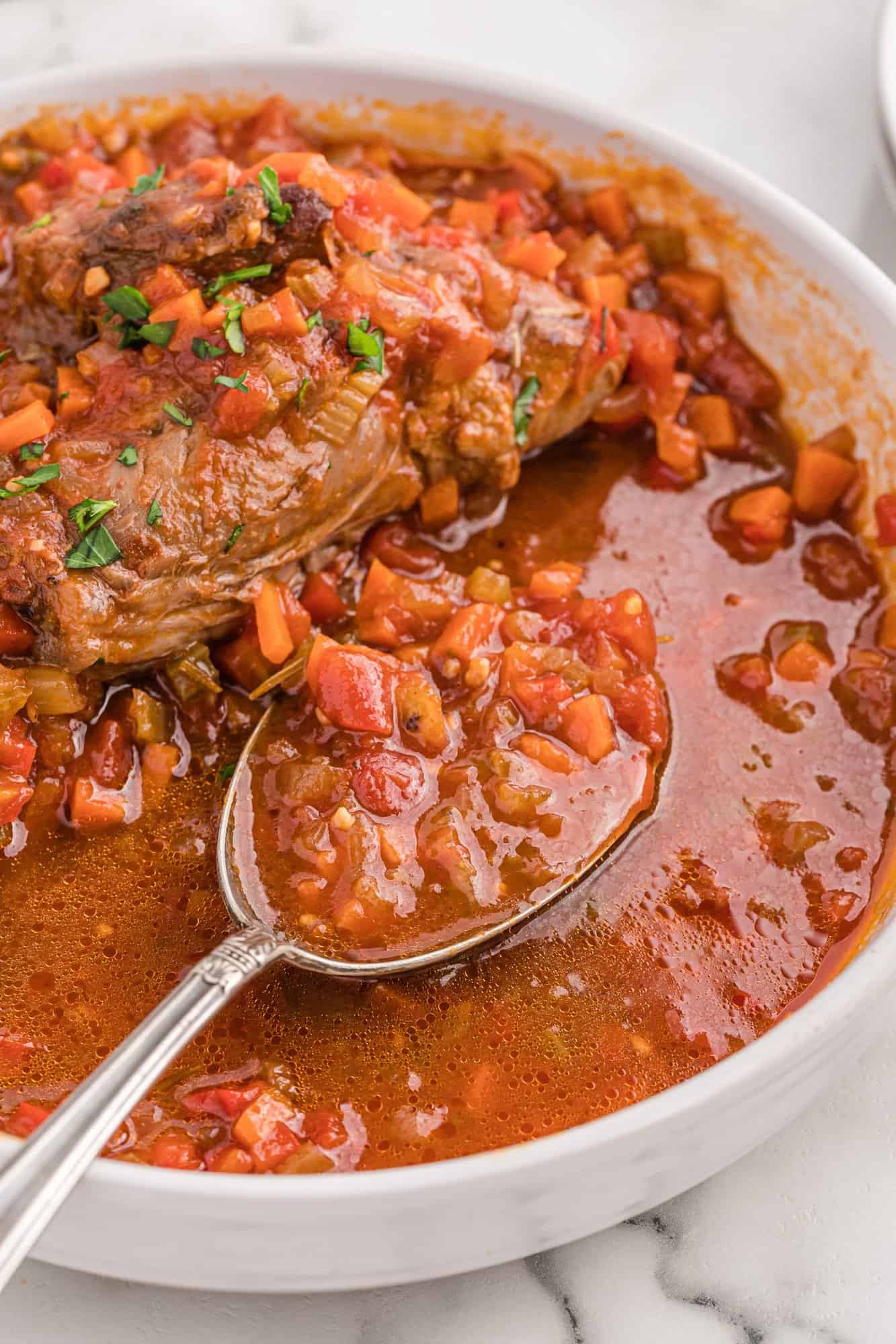 Braising liquid in a large spoon.