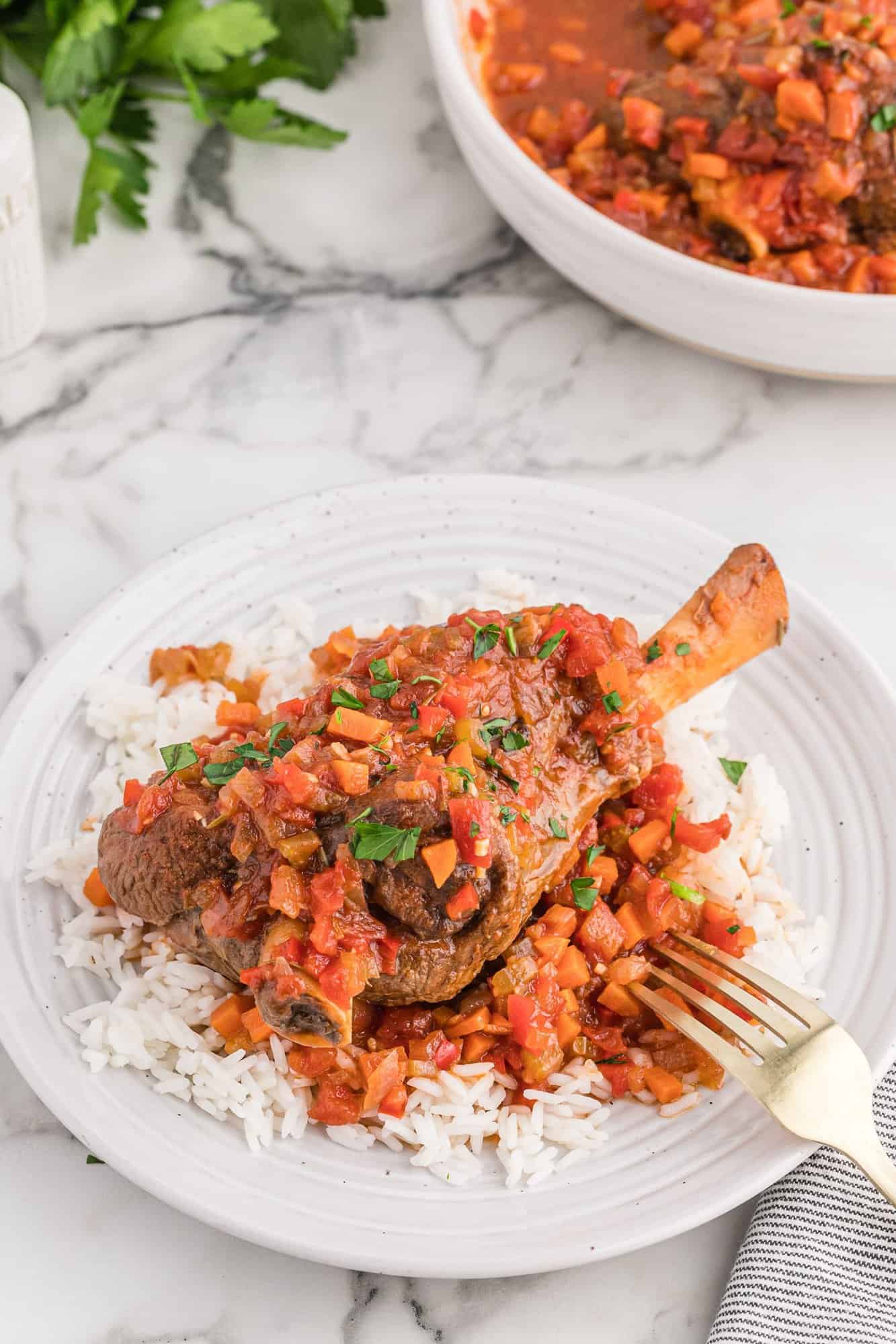 Braised lamb shank on a white plate.