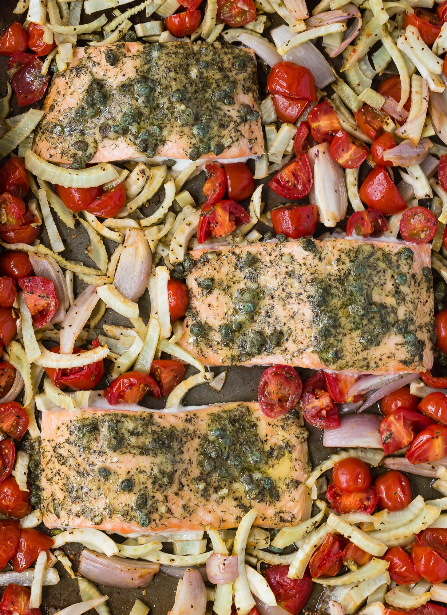 Overhead view of sheet pan with roasted salmon with tomatoes and fennel.
