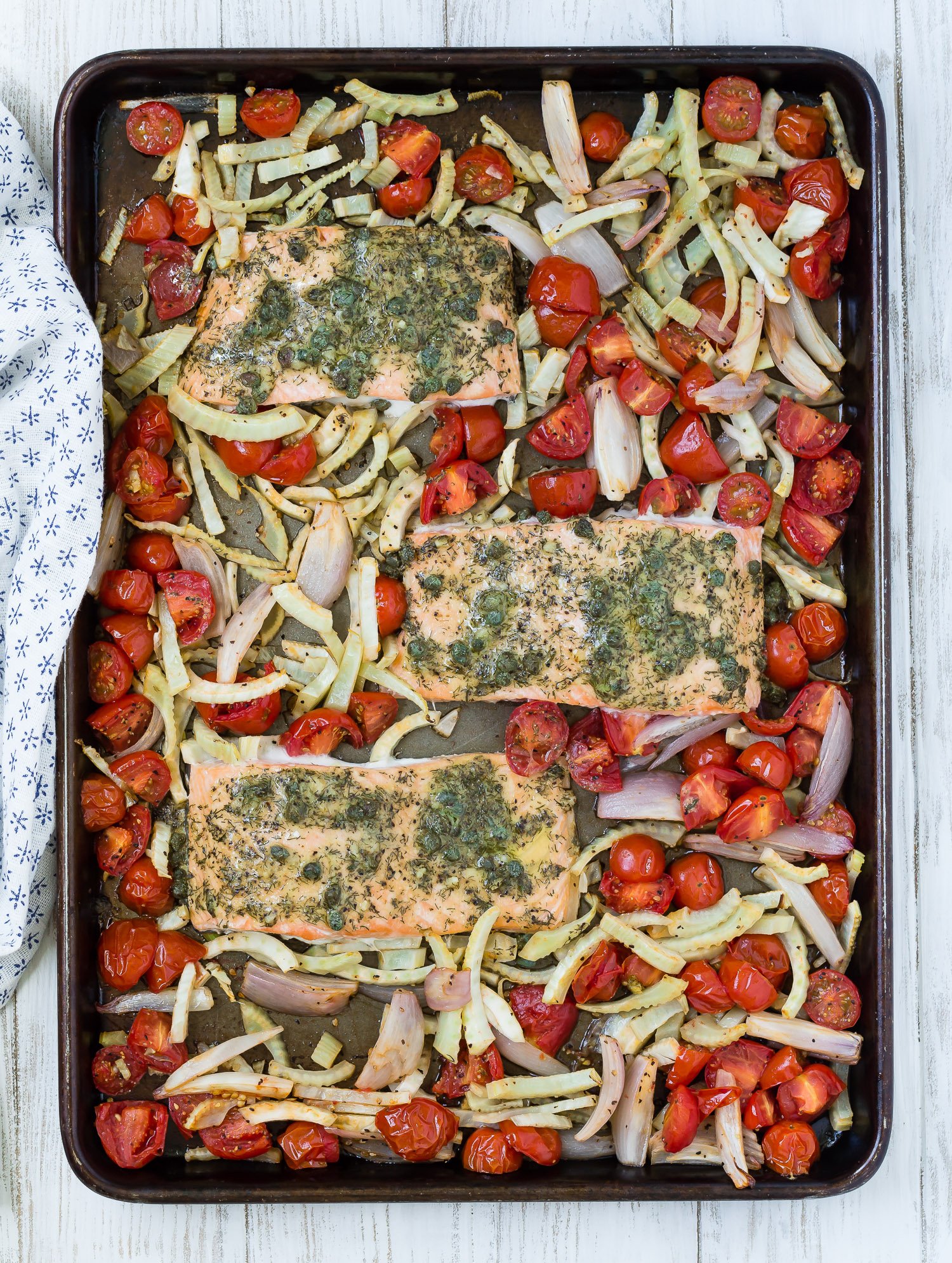 Salmon, fennel, and tomatoes on a sheet pan.