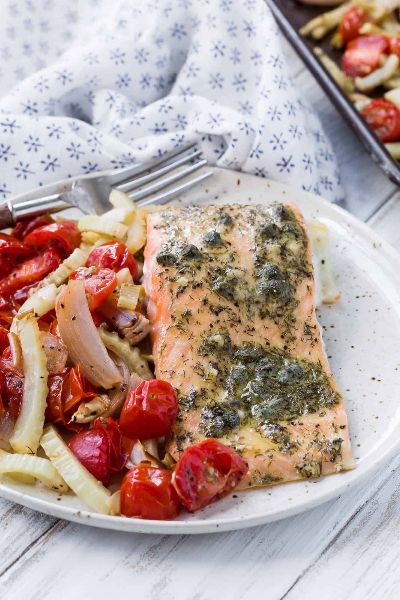 White plate with salmon, tomatoes, and fennel.