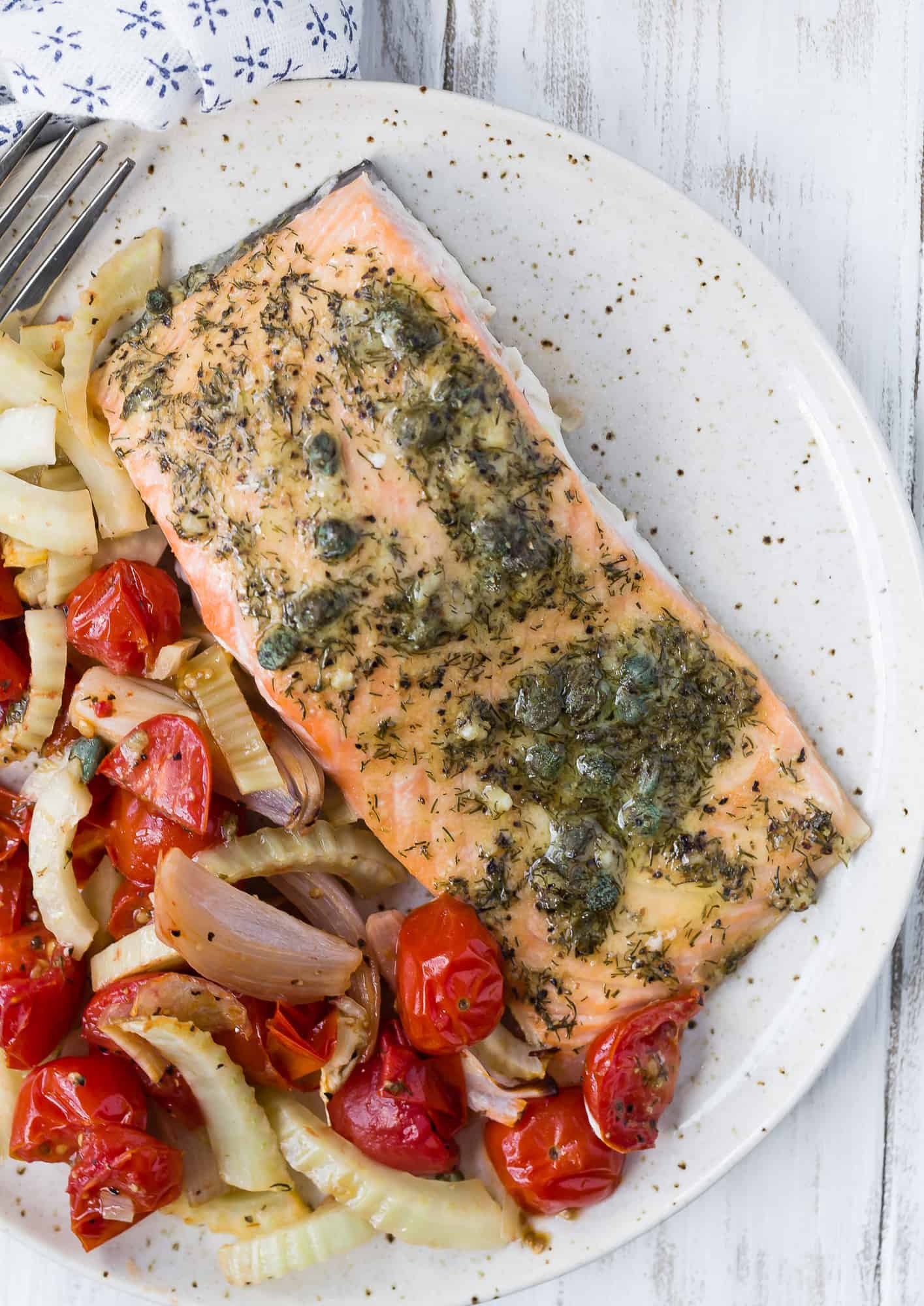 Plated cooked salmon with roasted tomatoes and fennel.