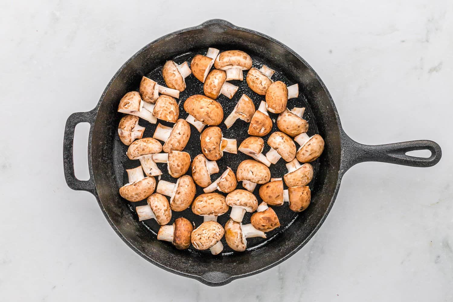 Halved mushrooms in a skillet.