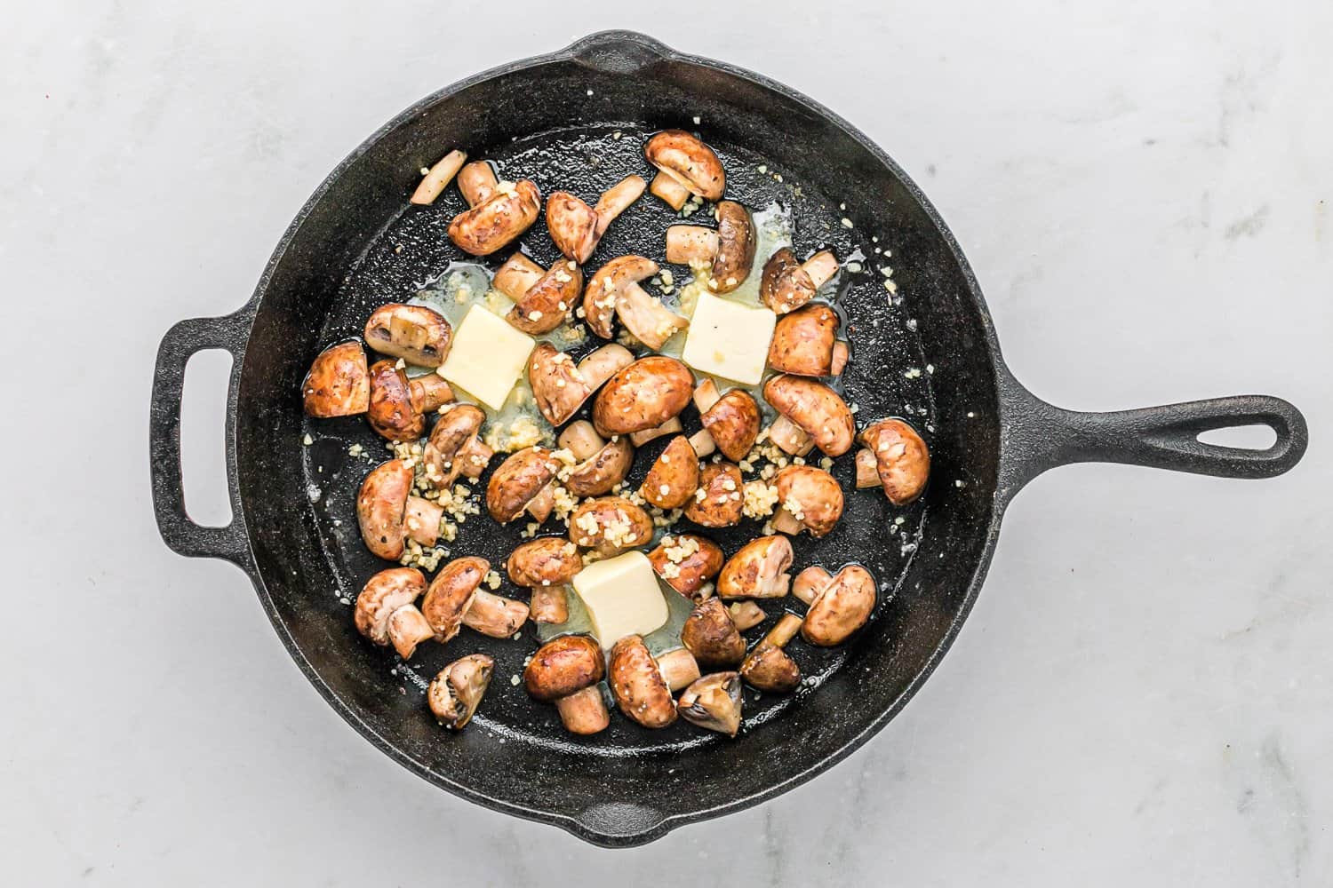 Butter, unmelted, in a pan with mushrooms.