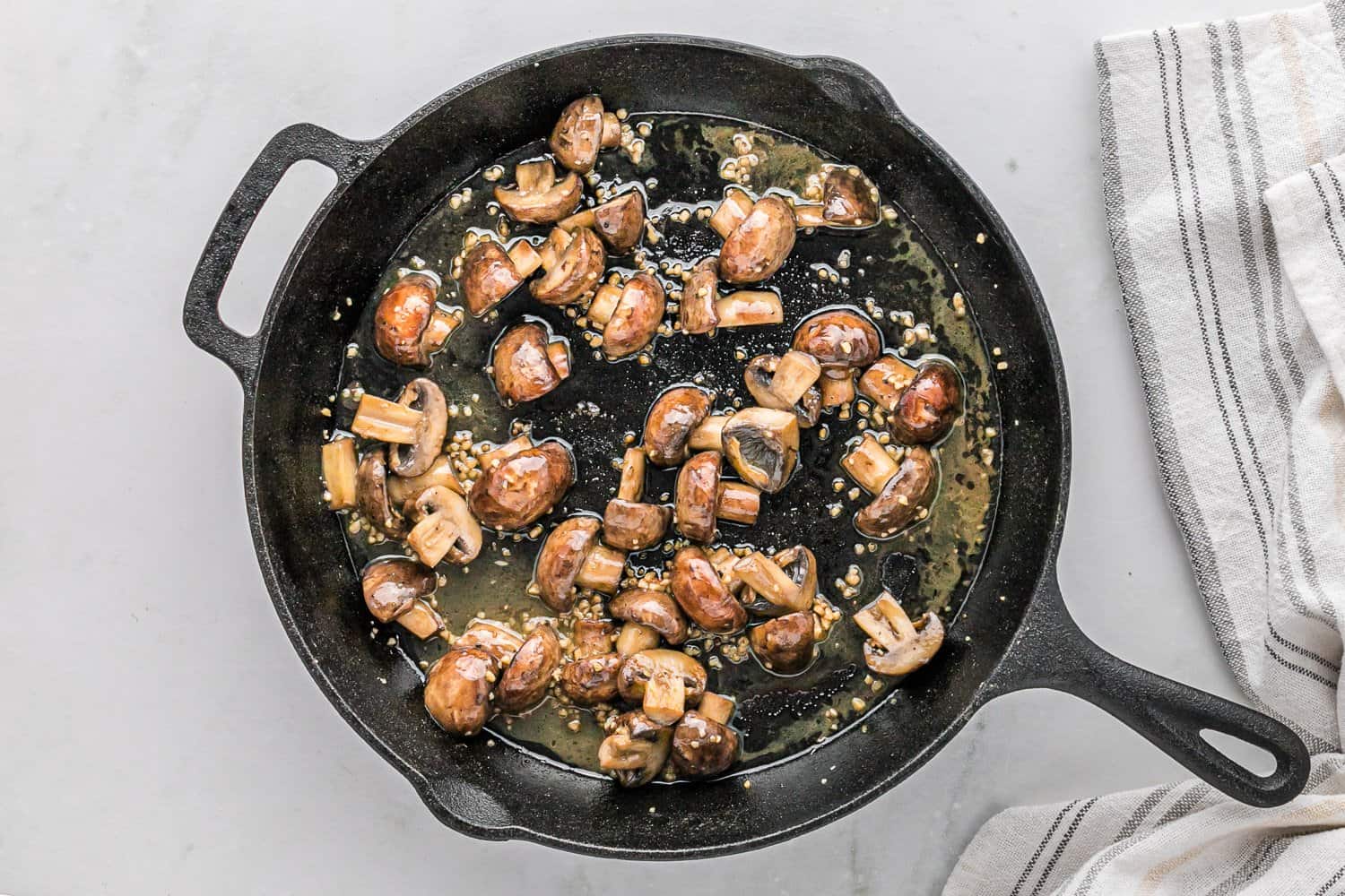 Sautéed mushrooms and melted butter in a pan.