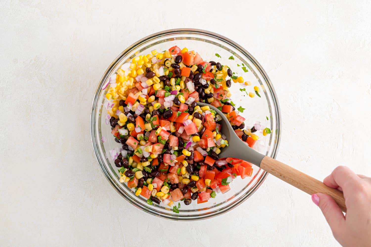 Salsa being stirred in a mixing bowl.