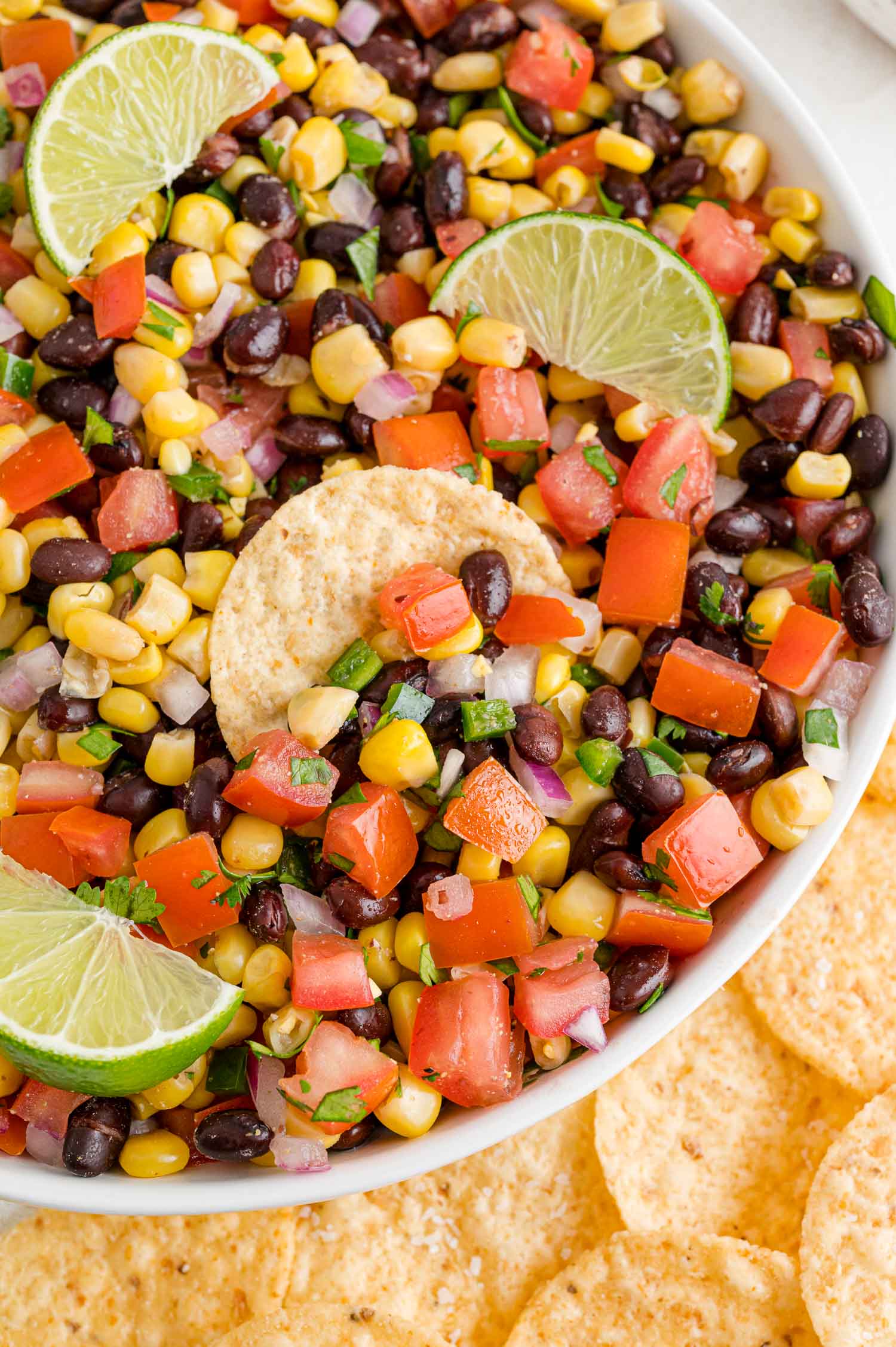 Black bean corn salsa in a bowl with a chip and lime wedges.
