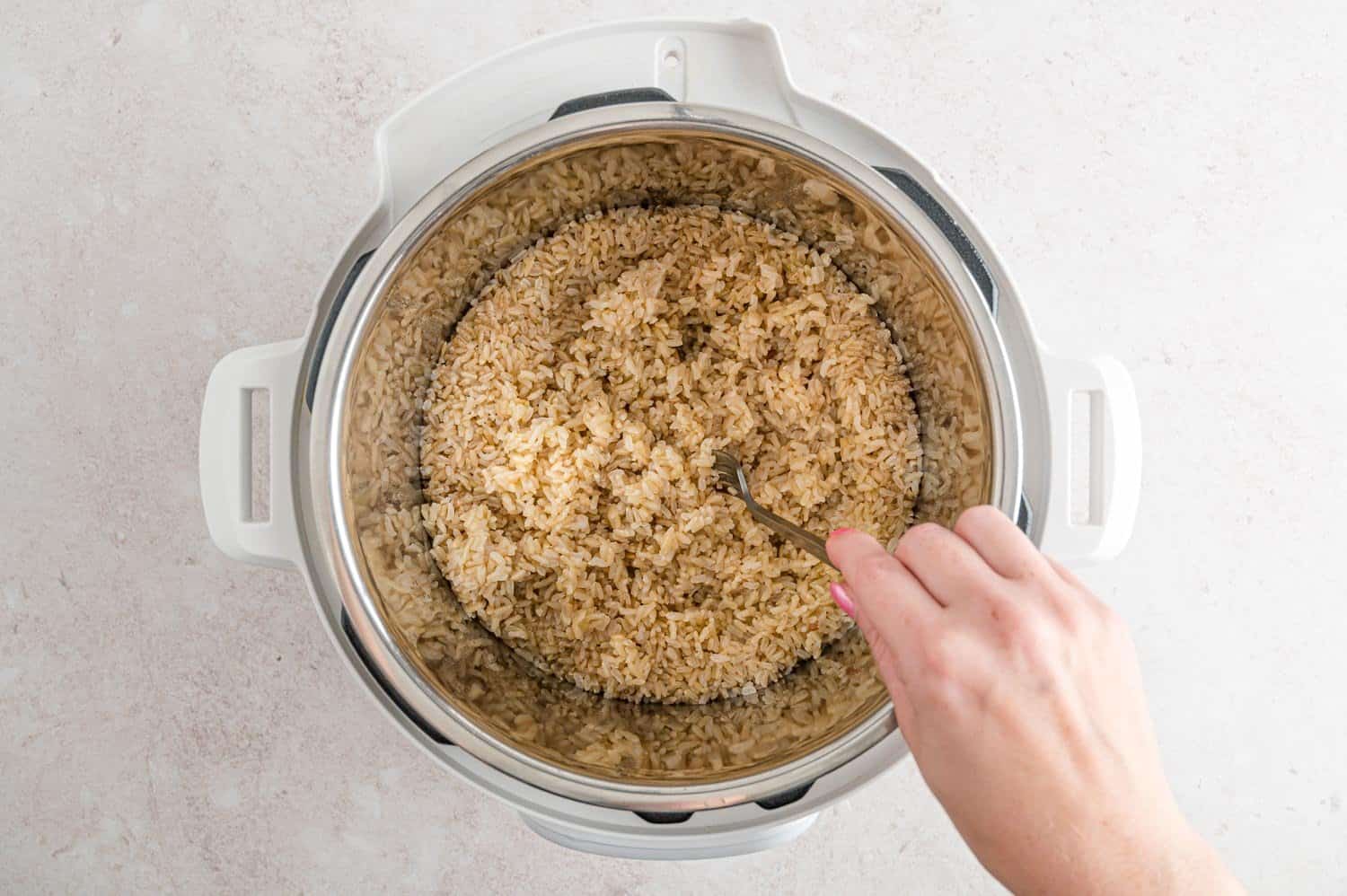 Brown rice being fluffed with a fork.