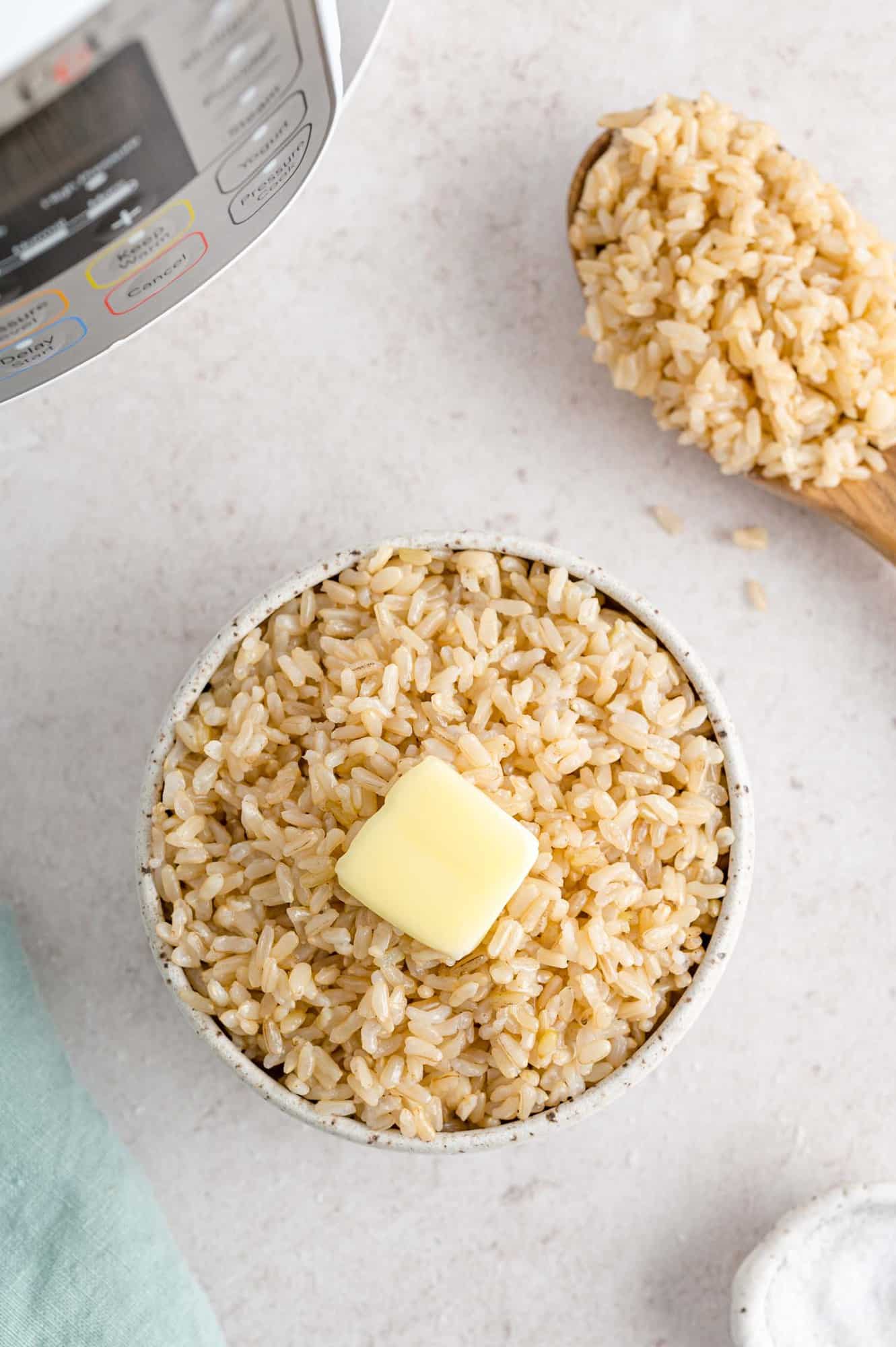 Rice in a bowl with butter, an instant pot in the background.