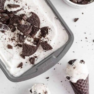 Cookies and cream ice cream in a pan and in cones.