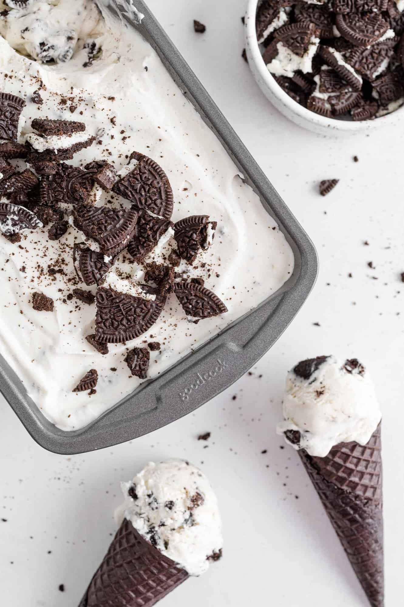 Cookies and cream ice cream in a pan and in cones.