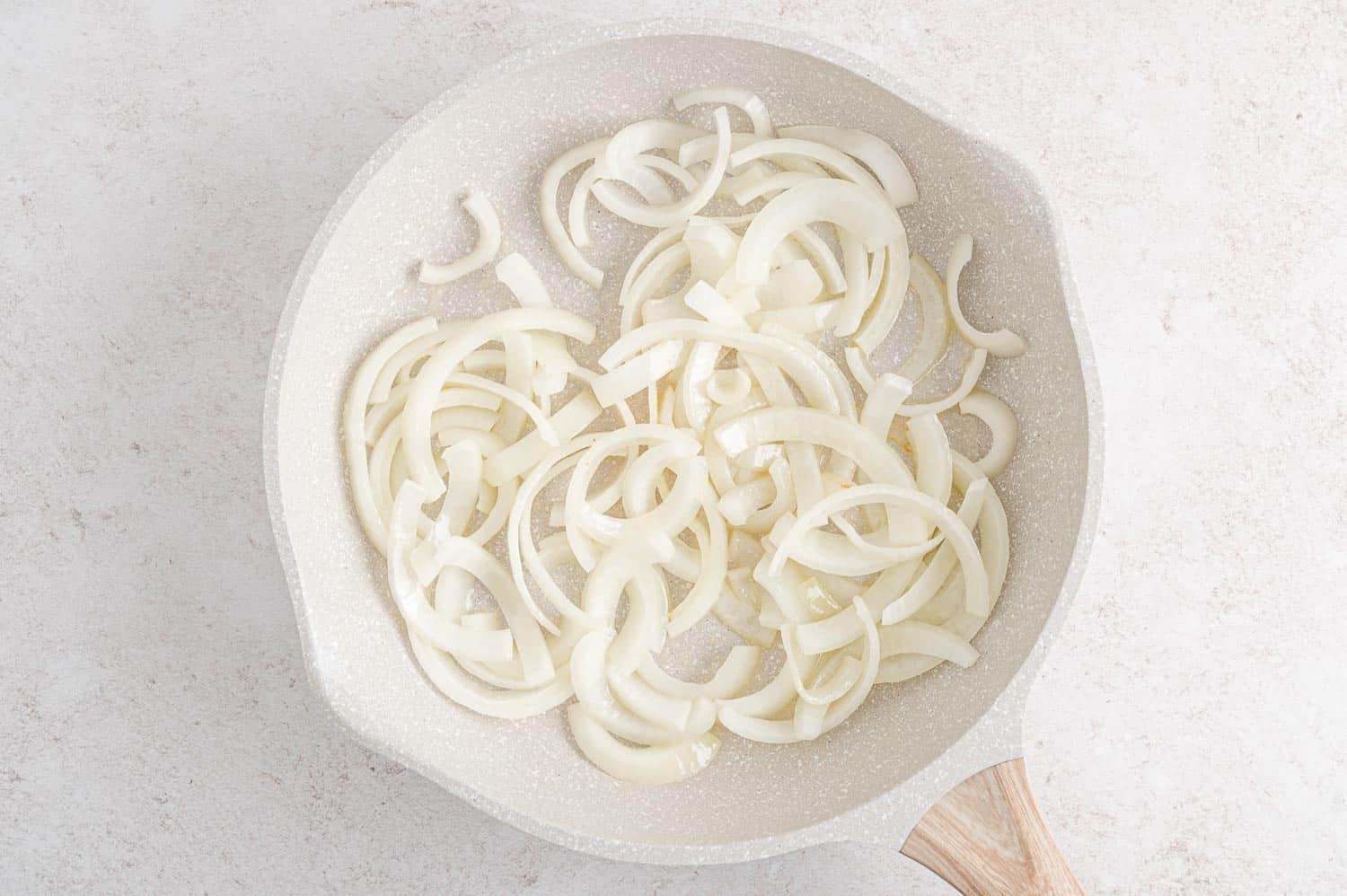 Uncooked onion in a frying pan.